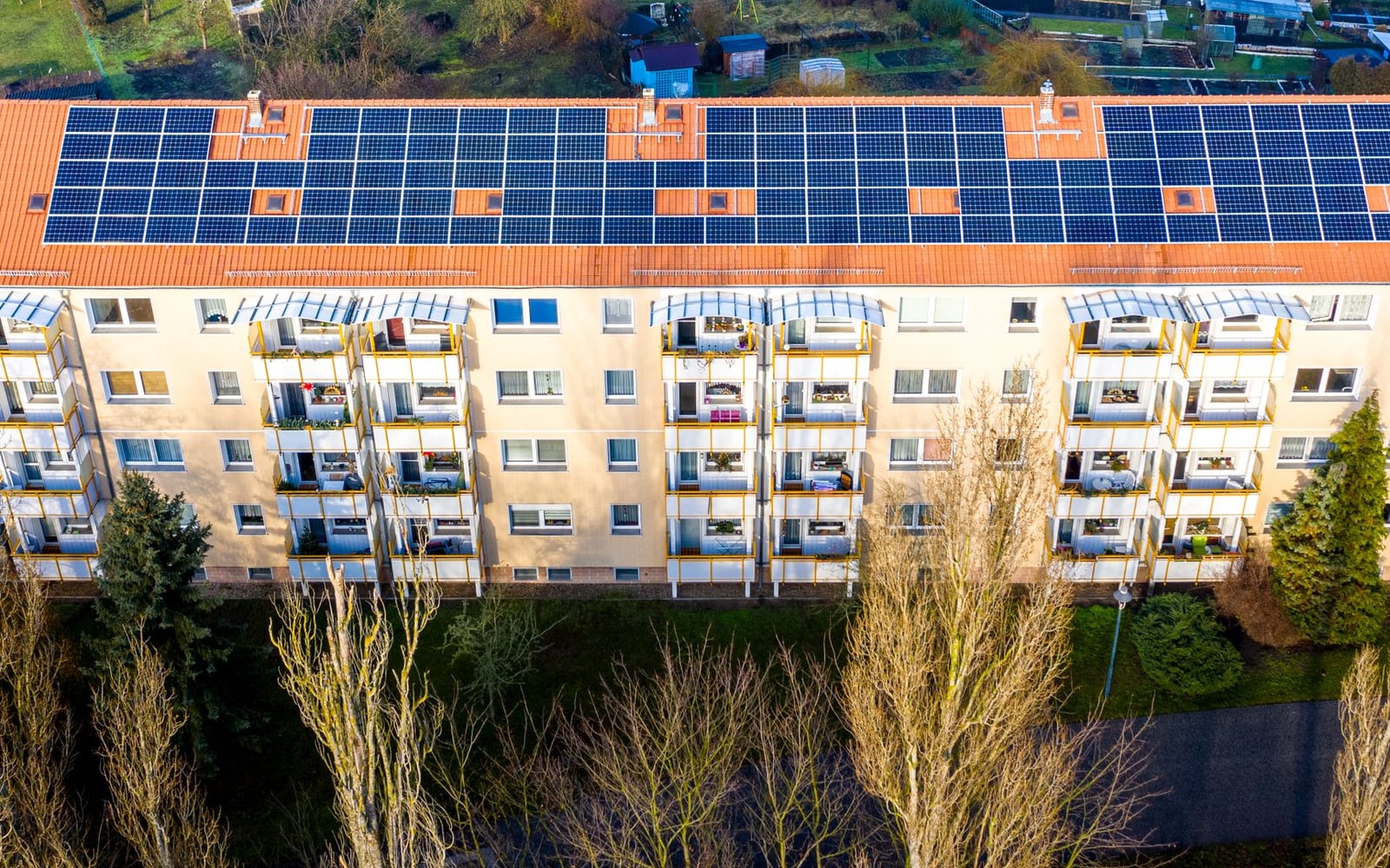 Çatısı boydan boya güneş paneliyle kaplı çok katlı apartman bloğunun havadan görünüşü